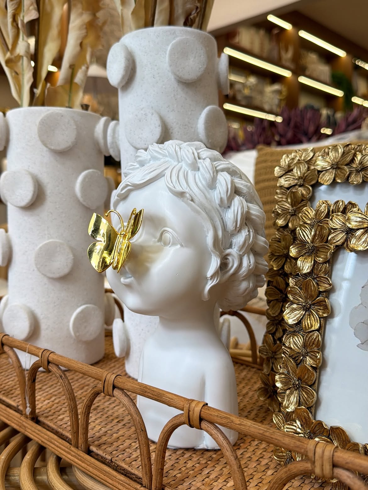 Escultura delicada ao lado de porta-retrato dourado